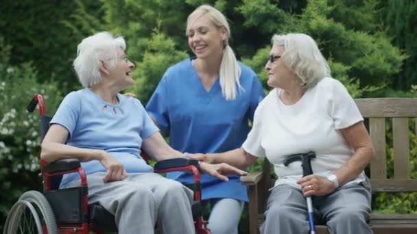 Cheerful elderly residents of nursing home spending time outdoors in the garden. - Filmati, video