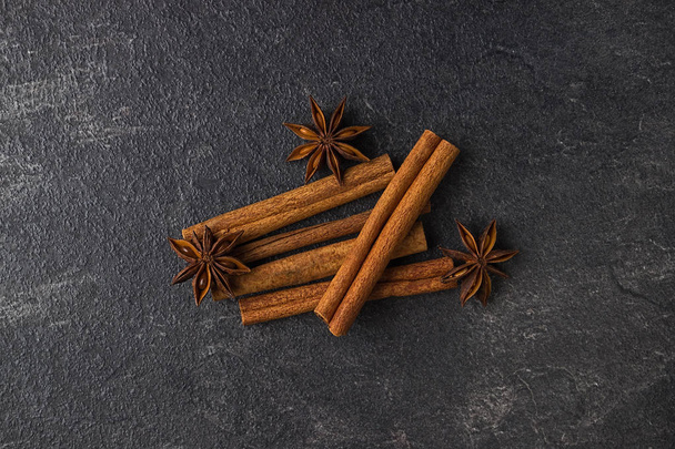 Cinnamon sticks and anise stars on a black stone background.  - Fotoğraf, Görsel