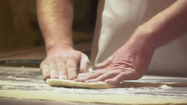 Делать пиццу или тесто крупным планом мужские руки в кондитерской кухне. Формирование теста является предшественником изготовления широкого спектра продуктов питания, в частности хлеба, печенья, тортов. Видео замедленного действия
. - Кадры, видео