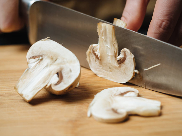 Donna che taglia funghi crudi su tavola di legno
 - Foto, immagini