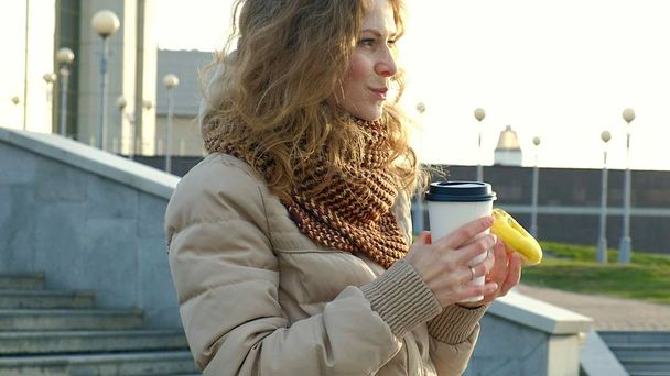 Gyönyörű fiatal nő italok kávé egy sétát a város - Fotó, kép
