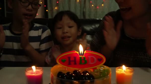Little asian girl blowing out birthday candles with her family  - Footage, Video