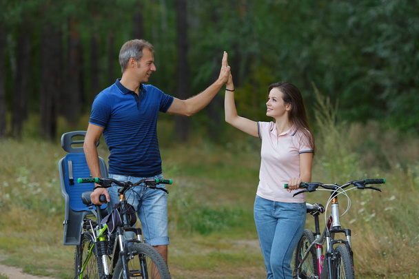 Happy couple with bikes funs in pine forest - Photo, Image