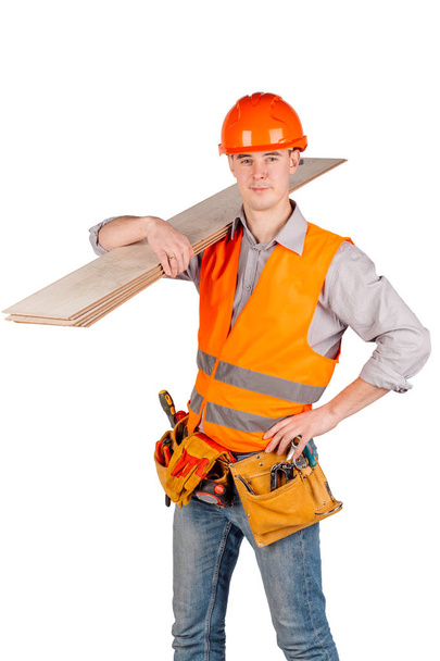 builder in a helmet holding floorboards and looking at camera over white wall background. repair, construction, building, people and maintenance concept. - 写真・画像
