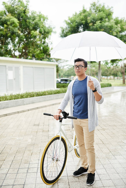 Βιετναμέζικα-άνθρωπος με ποδήλατο και ομπρέλα στέκεται σε εξωτερικούς χώρους - Φωτογραφία, εικόνα