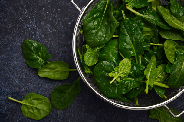 Fresh green spinach leaves on a dark concrete background, top view, flat lay. - Photo, Image