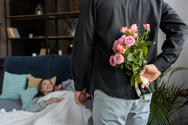 boyfriend hiding bouquet of roses from girlfriend on international womens day - Foto, imagen