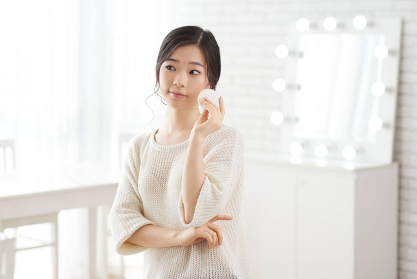 Mooie jonge Aziatische vrouw met wattenschijfje in haar hand - Foto, afbeelding