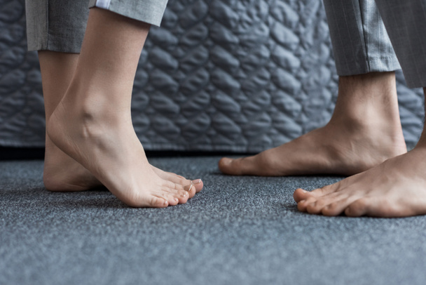 cropped image of boyfriend and girlfriend standing barefoot on floor - Foto, imagen