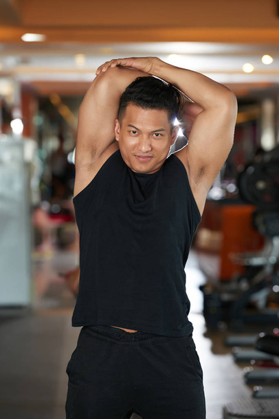 Uśmiechający się Malaysian sportowca rozciągania po treningu ramion - Zdjęcie, obraz