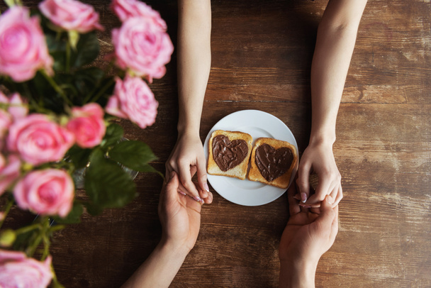 image recadrée de couple tenant la main près des toasts avec de la pâte de chocolat en forme de cœur, concept de Saint-Valentin
 - Photo, image