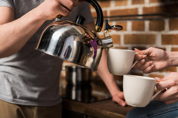 cropped image of boyfriend pouring coffee in cups - Fotó, kép