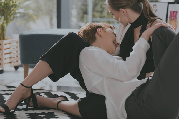 stylish young lesbian couple cuddling on floor - Фото, изображение