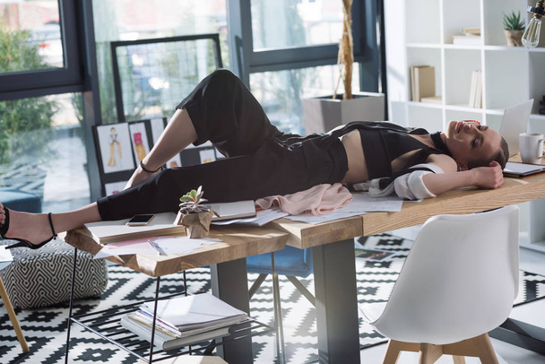 overworked stylish fashion designer sleeping on work desk - Foto, Imagem