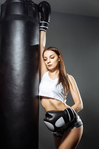 Portrait of a young beautiful woman with boxing gloves in the gym - Foto, afbeelding