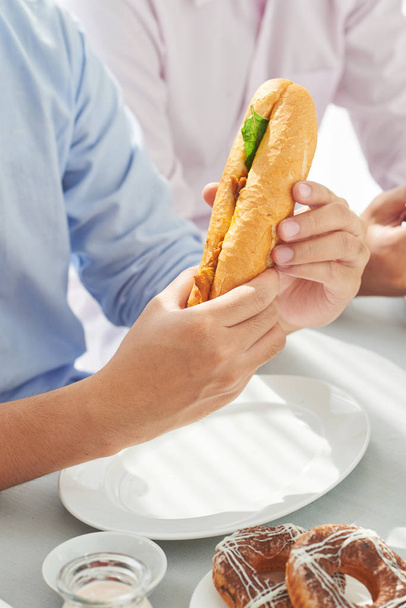 Close-up image of big sandwich in hands of man - Foto, afbeelding