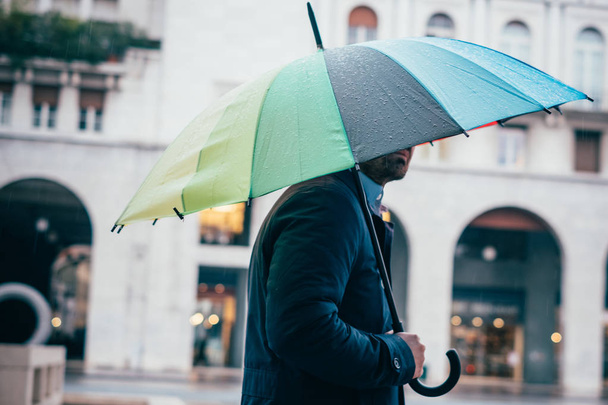 Deszczowy dzień w mieście i biznesmen gospodarstwa parasol - Zdjęcie, obraz