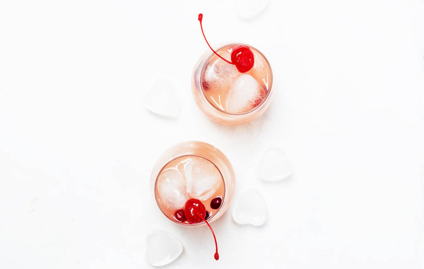 Cold winter pink cocktail for Valentine day, two glasses, white background with iced hearts, top view - Фото, изображение