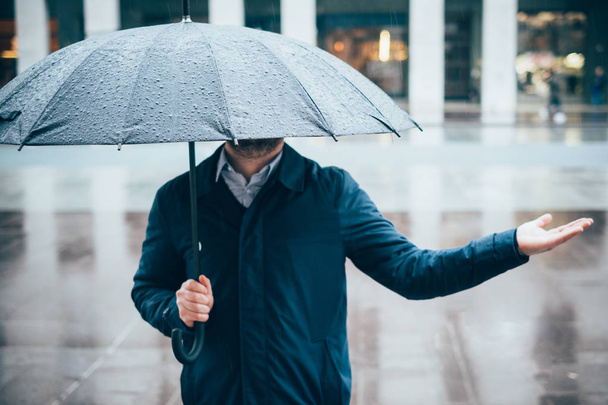 Mężczyznę idącego w mieście z parasolem na deszczowy dzień - Zdjęcie, obraz