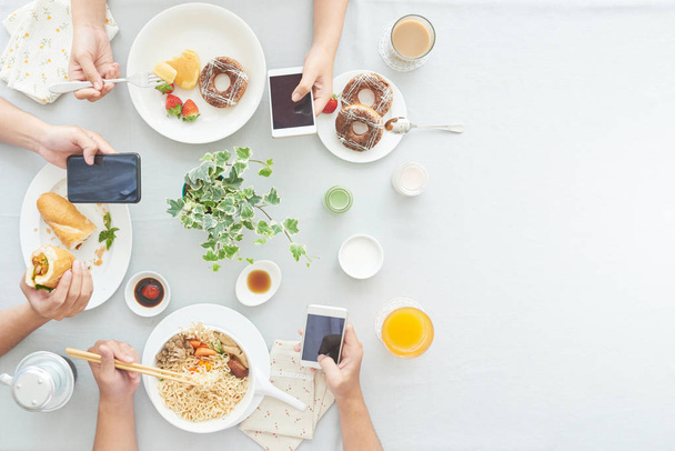 Las personas que leen noticias en sus teléfonos cuando desayunan, ven desde arriba
 - Foto, imagen