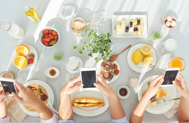 Handen van mensen met behulp van smartphones tijdens het ontbijt - Foto, afbeelding