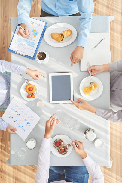 Gente de negocios viendo la presentación en tableta y almorzando
 - Foto, imagen