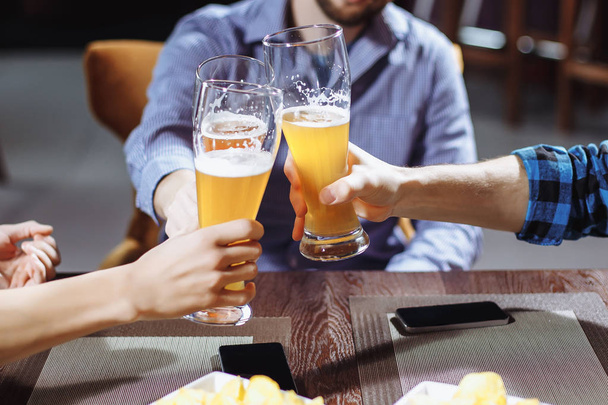 Three friends toasting with glasses of light beer at the pub - Photo, Image