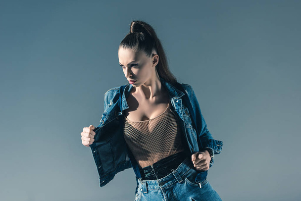 sexy young woman posing in trendy denim clothes, isolated on grey - Zdjęcie, obraz