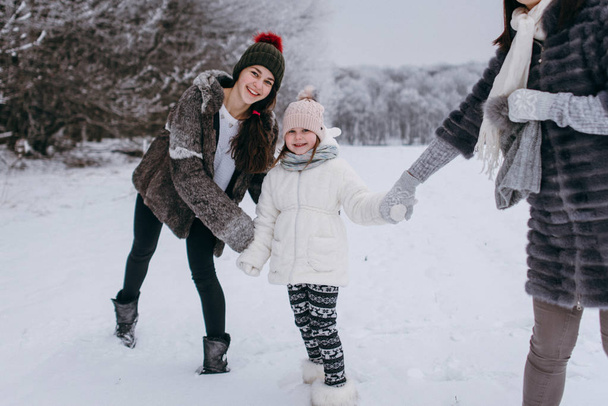 Madre divirtiéndose y bromeando con las hijas en el parque de invierno
  - Foto, Imagen