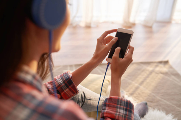 Γυναίκα να ακούτε μουσική στο smartphone, θέα πάνω από τον ώμο - Φωτογραφία, εικόνα