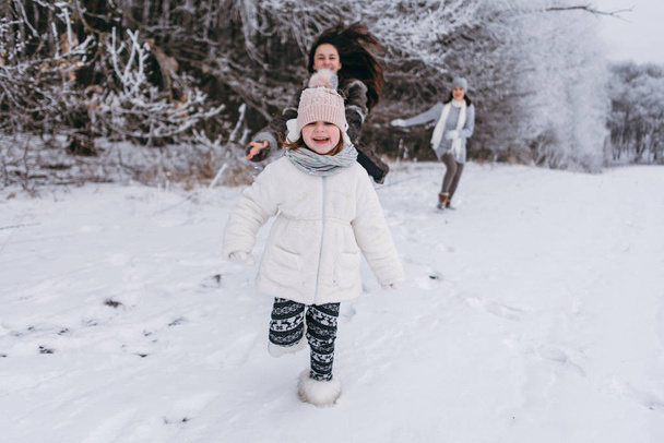 Mother with daughters running and having fun outside in winter time - 写真・画像