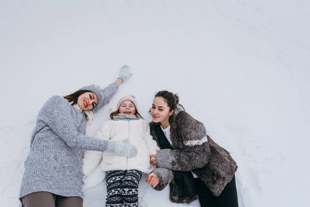 Moeder met dochters knuffelen op sneeuw - Foto, afbeelding