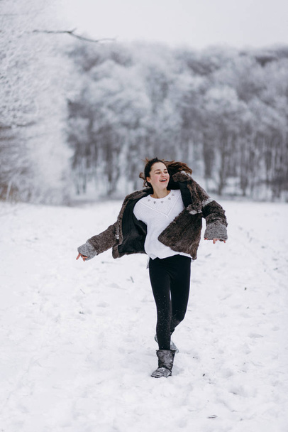 Vista de la adolescente divirtiéndose y corriendo en el bosque de invierno
 - Foto, imagen