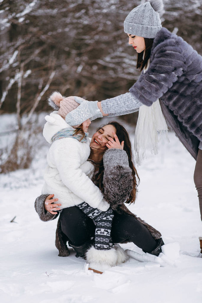 Mutter spielt mit Töchtern und hat Spaß im Winterpark - Foto, Bild