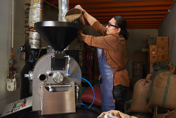 Rösterei-Besitzer stellt Container mit grünen Kaffeebohnen in Röster - Foto, Bild