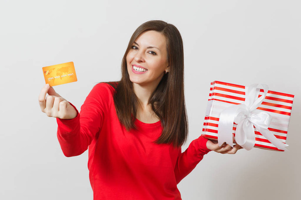 Hermosa mujer sosteniendo tarjeta de crédito, caja de regalo roja con regalo aislado sobre fondo blanco. Para publicidad. Día de San Valentín, Día Internacional de la Mujer, Navidad, cumpleaños, concepto de fiesta
. - Foto, imagen
