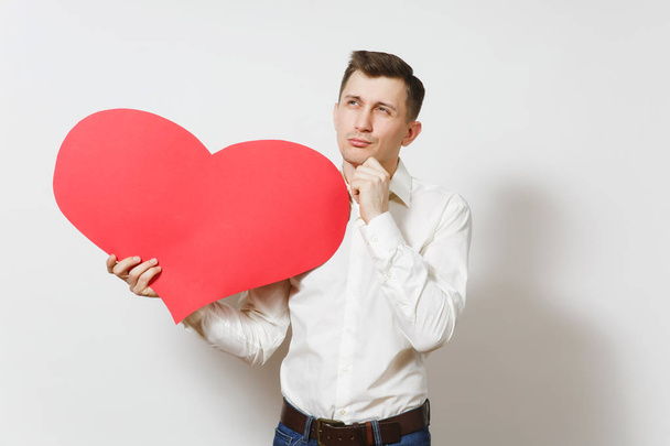 Young handsome man in shirt holding big red heart isolated on white background. Copy space, advertisement. Place for text. St. Valentine's Day, International Women's Day, birthday, holiday concept. - Фото, изображение