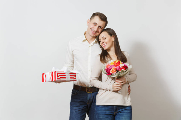 Young couple in love. Man and woman with bouquet of beautiful roses flowers, present box with gift isolated on white background. St. Valentine's Day, International Women's Day birthday holiday concept - Valokuva, kuva