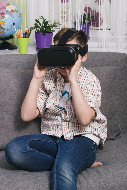 Poika leikkii virtuaalitodellisuuslaseilla sisätiloissa. Digitaalinen virtuaalitodellisuus laite
 - Valokuva, kuva