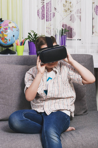 Boy plays with virtual reality glasses, indoors. Digital virtual reality device - Фото, зображення