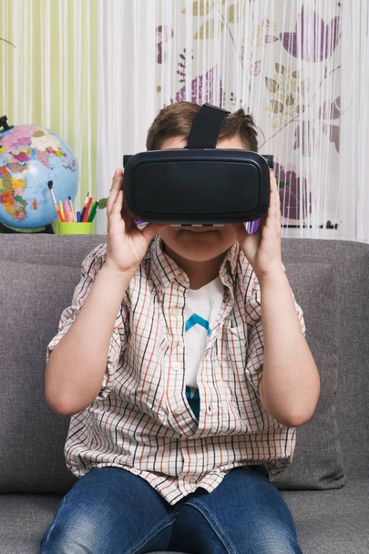 Αγόρι παίζει με γυαλιά εικονικής πραγματικότητας, σε εσωτερικούς χώρους. Συσκευή ψηφιακής εικονικής πραγματικότητας - Φωτογραφία, εικόνα