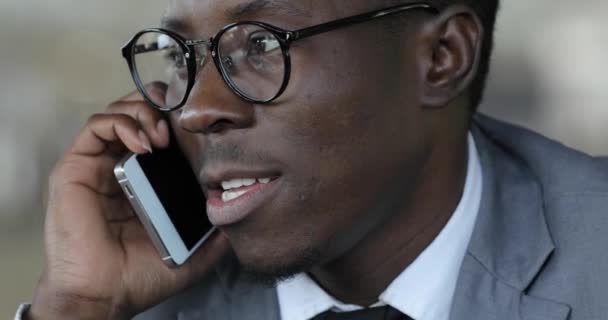 Hombre de negocios africano hablando por teléfono inteligente en primer plano cafetería
 - Metraje, vídeo