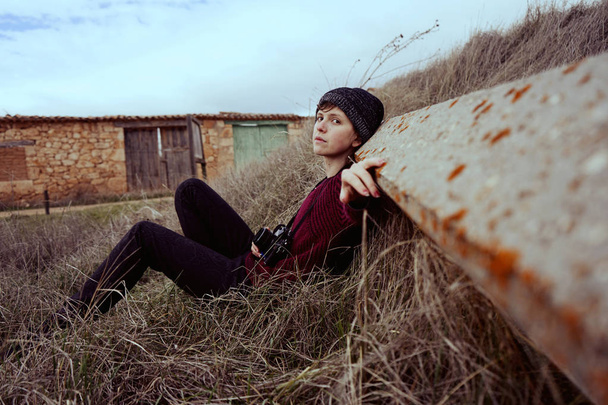 Young woman in red sweater and hat posing outdoor in dry grass - Valokuva, kuva