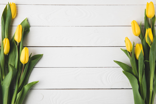 Draufsicht auf schöne gelbe Tulpenblüten auf weißer Holzoberfläche      - Foto, Bild