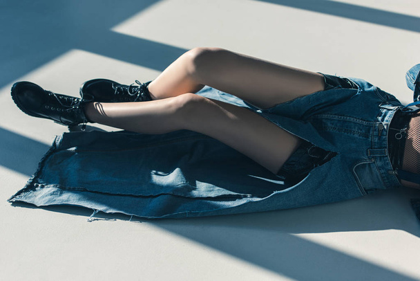 cropped view of girl in denim clothes lying on floor with shadows - Fotografie, Obrázek