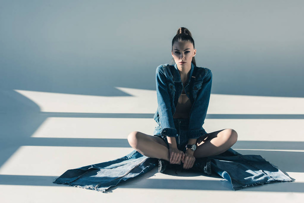caucasian woman in denim clothes sitting on floor with shadows - Zdjęcie, obraz