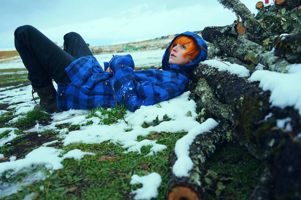 Młoda Ruda Kobieta w niebieski zimowa kurtka pozowanie odkryty na snowy zaloguje się na tle nieba - Zdjęcie, obraz