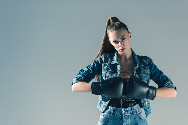 stylish girl in denim clothes and boxing gloves, isolated on grey - Фото, изображение