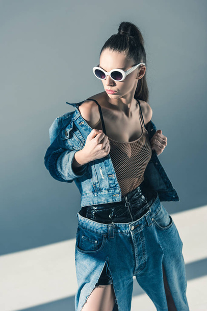 fashionable model posing in denim style and sunglasses - Photo, Image