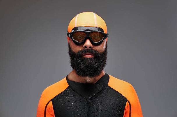 Yakın çekim turuncu neopren dalgıç elbisesi ve gri arka plan üzerinde izole dalış maske sakallı bir erkek portresi. - Fotoğraf, Görsel